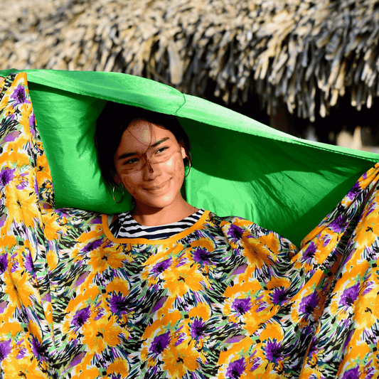 Wayuu woman dancing joyfully in traditional attire, surrounded by a natural desert landscape.