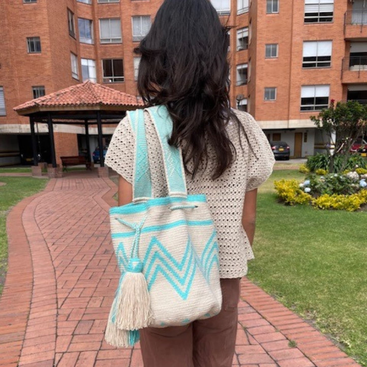 A simple yet captivating beige Wayuu bag adorned with aqua patterns, showcasing a minimalist design with intricate woven details.