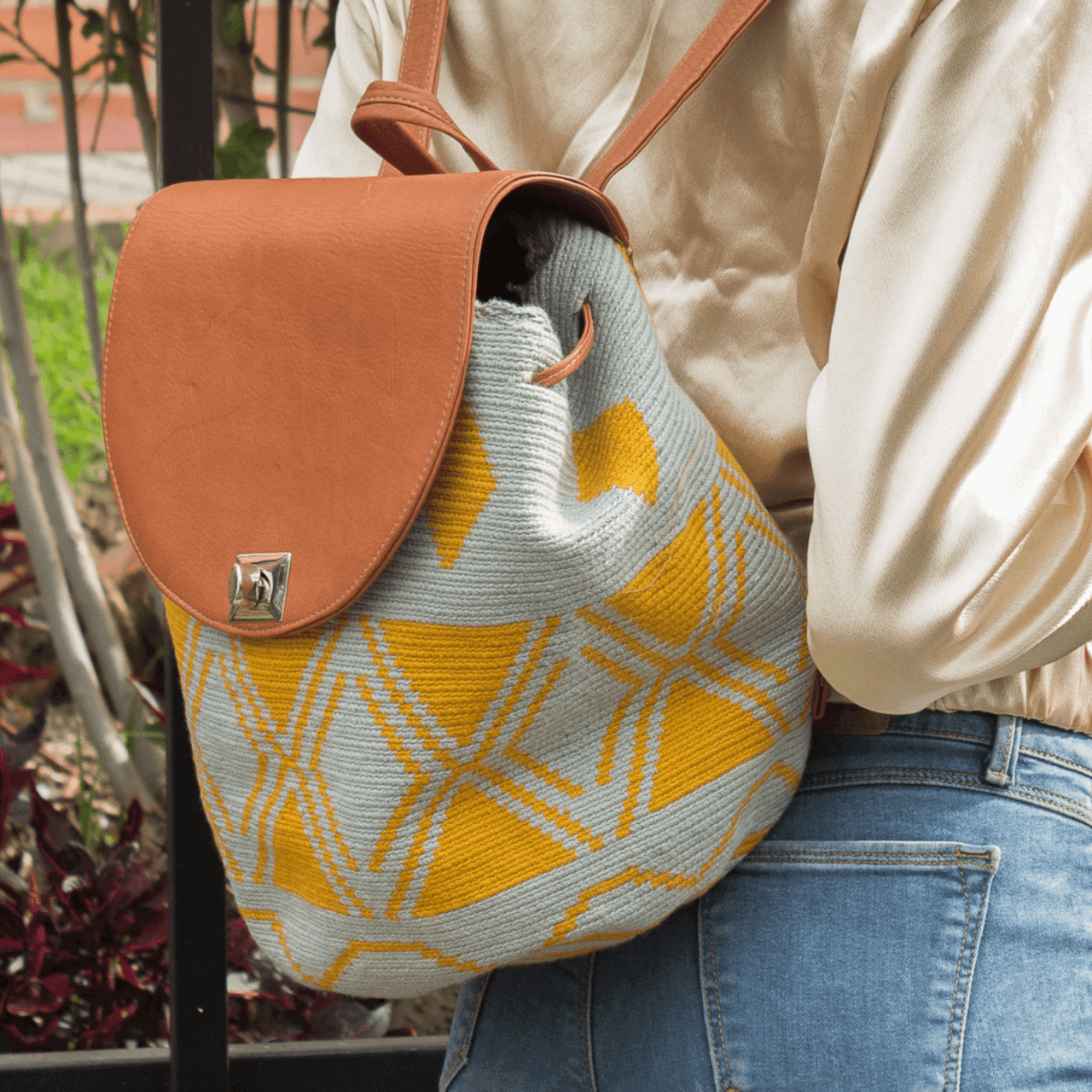 Taganga leather backpack featuring a stunning Wayuu pattern in a captivating blend of blue-gray and ochre colors. The design is accentuated with natural genuine leather, creating a beautiful contrast. This versatile bag is perfect for day outings or short trips, offering a lightweight and comfortable carrying experience.