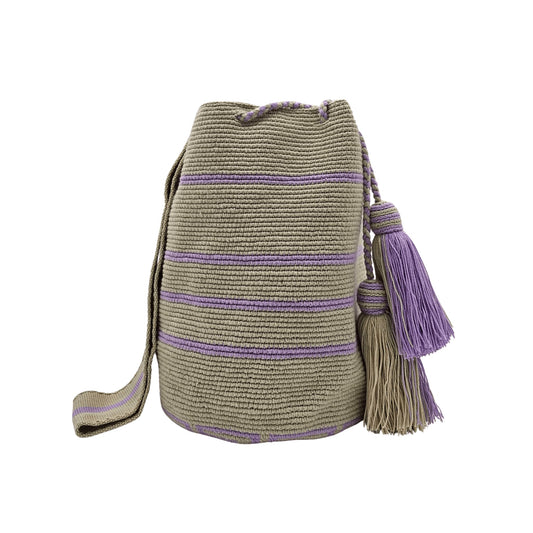 Handwoven Wayuu bag in beige with delicate lavender stripes, featuring a braided shoulder strap and decorative tassels. Ethically crafted by Colombian artisans using traditional crochet techniques.