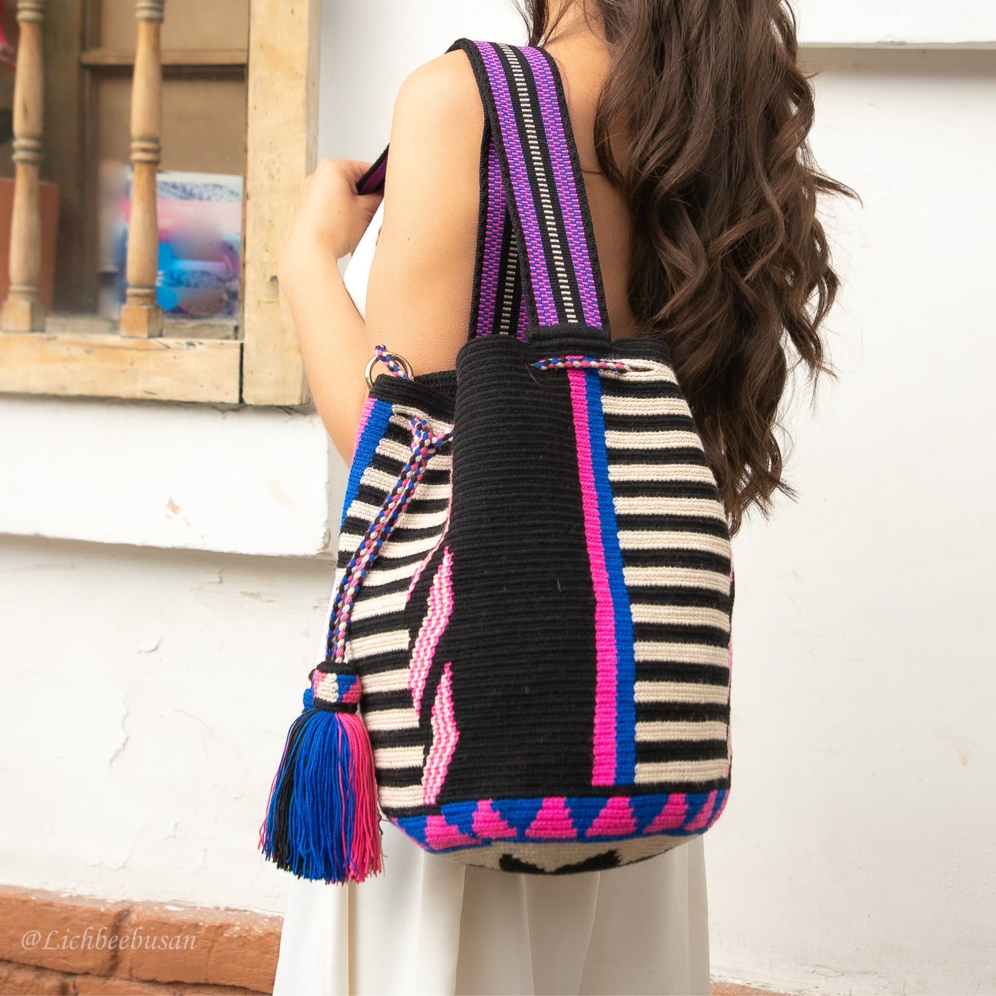 A handmade Wayuu Mochila bag from Colombia, featuring a striking striped design and a separate pouch for small essentials.