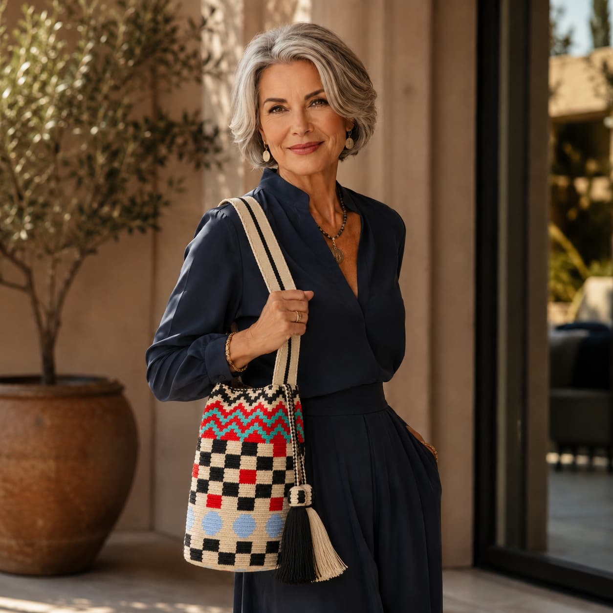 Handmade multicolored Wayuu bag with flat woven strap and geometric pattern, tassel detail, and vibrant artisanal design.