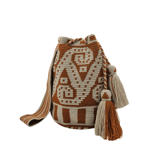 A Wayuu bag with a brown background and intricate woven patterns in a lighter beige color. The bag has a drawstring closure with long tassels.