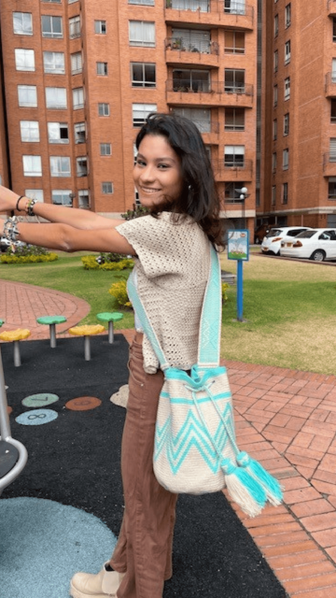 A simple yet captivating beige Wayuu bag adorned with aqua patterns, showcasing a minimalist design with intricate woven details.