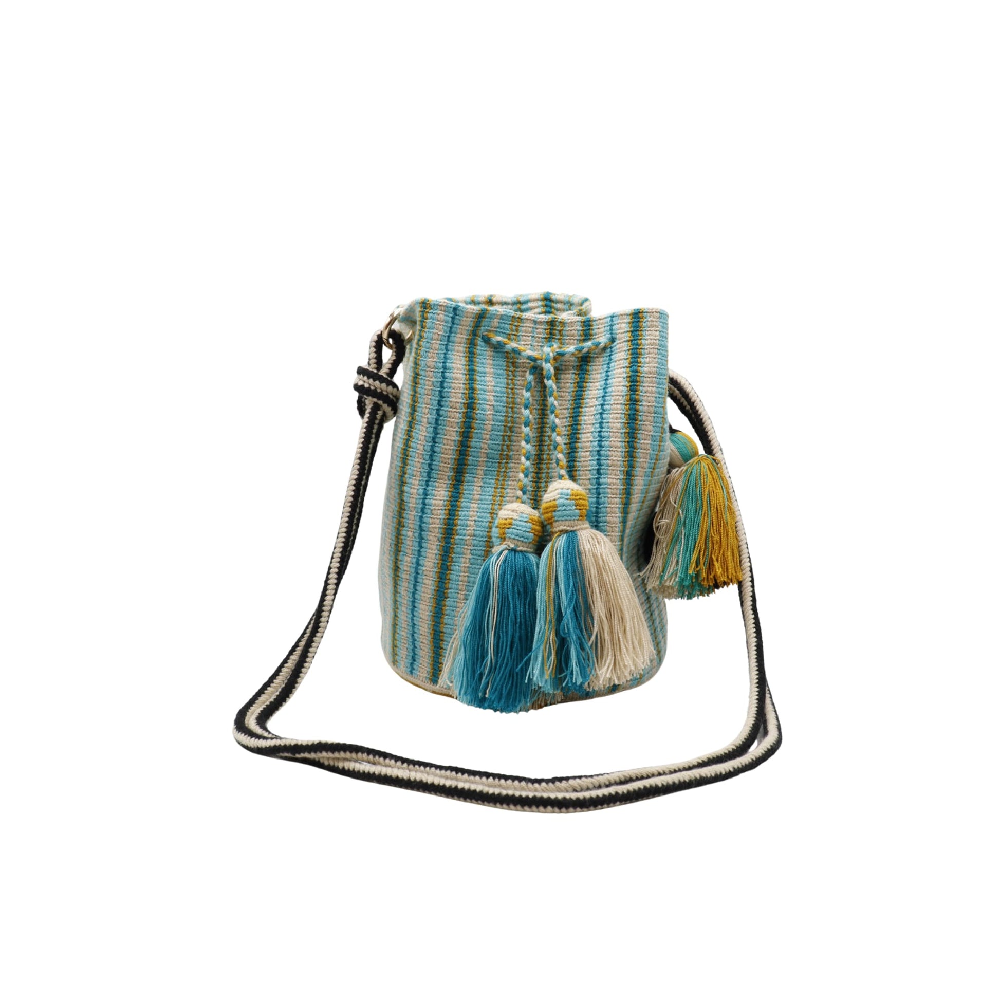 A handcrafted Wayuu bag with a vibrant striped pattern in turquoise, white, and yellow. The bag features a single long, braided black-and-white shoulder strap, a drawstring closure, and decorative tassels with a black pompoms accent.