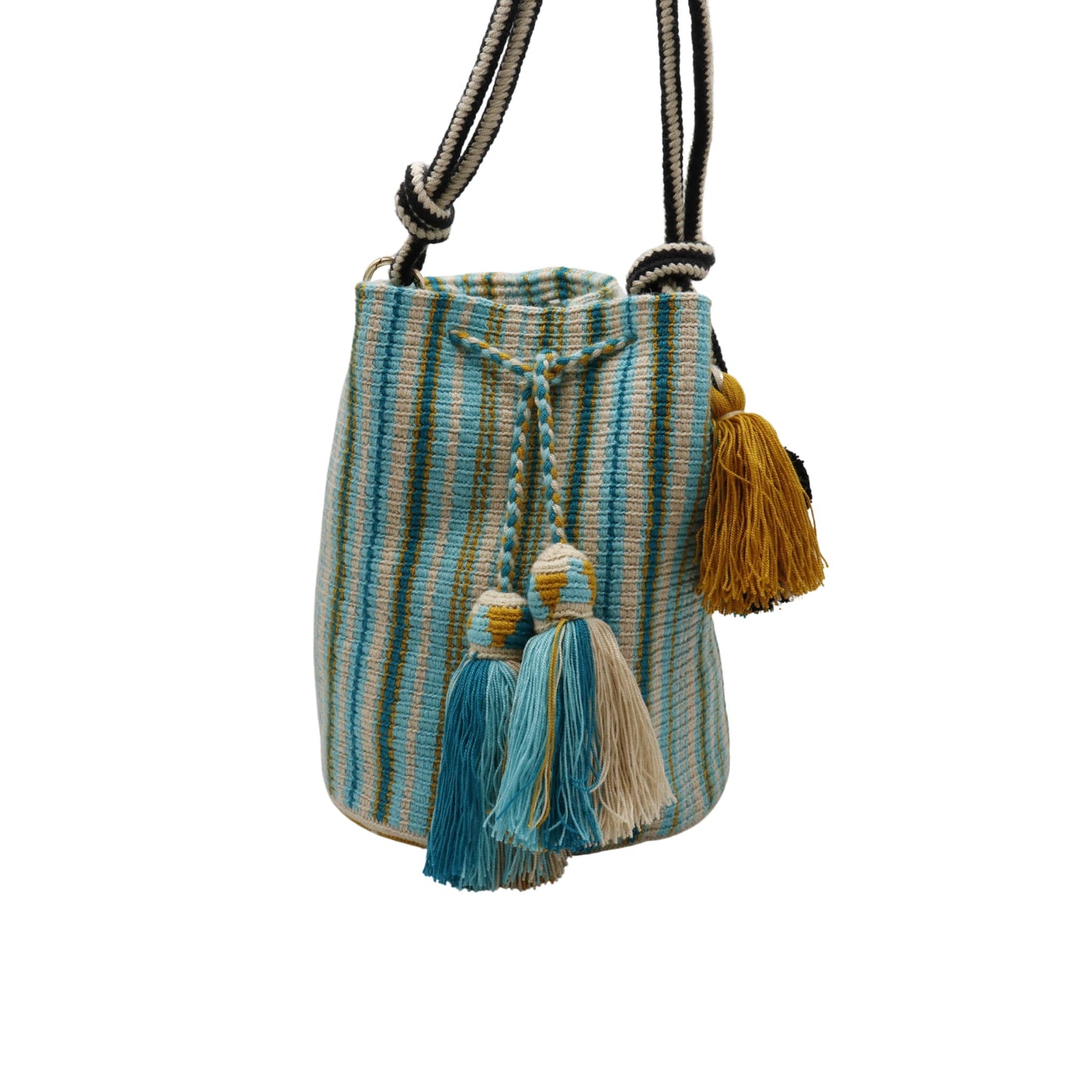 A handcrafted Wayuu bag with a vibrant striped pattern in turquoise, white, and yellow. The bag features a single long, braided black-and-white shoulder strap, a drawstring closure, and decorative tassels with a black pompoms accent.
