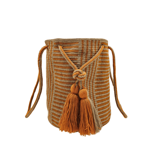 A Wayuu bag with a rusty orange background and a woven geometric pattern in beige. The bag has a drawstring closure with long tassels.