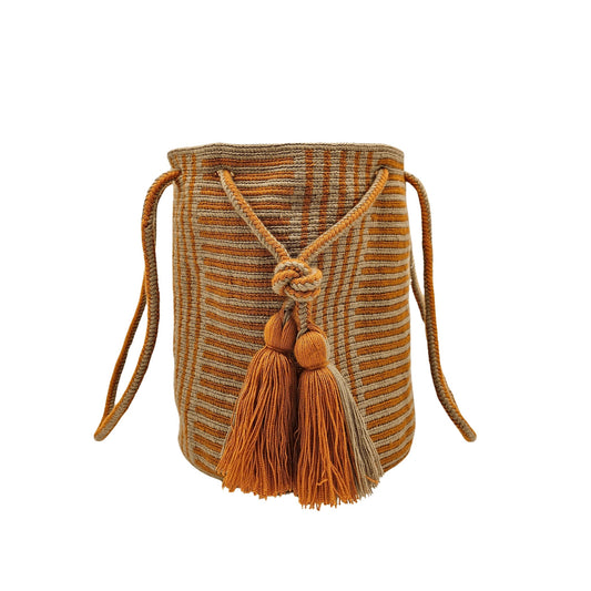 A Wayuu bag with a rusty orange background and a woven geometric pattern in beige. The bag has a drawstring closure with long tassels.