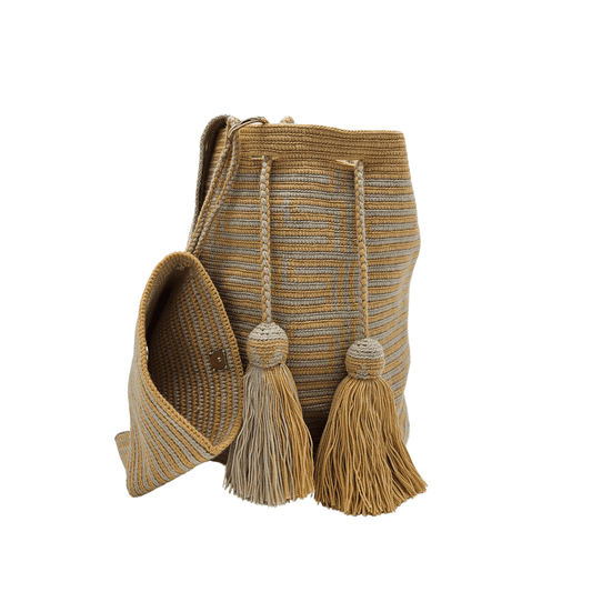 A Wayuu bag with a honey-colored background and a woven striped pattern in a lighter beige. It has a drawstring closure with long tassels and comes with a matching pouch.