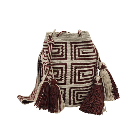 A beige Wayuu Mochila bag with a brown geometric pattern. It has a drawstring closure with tassels.