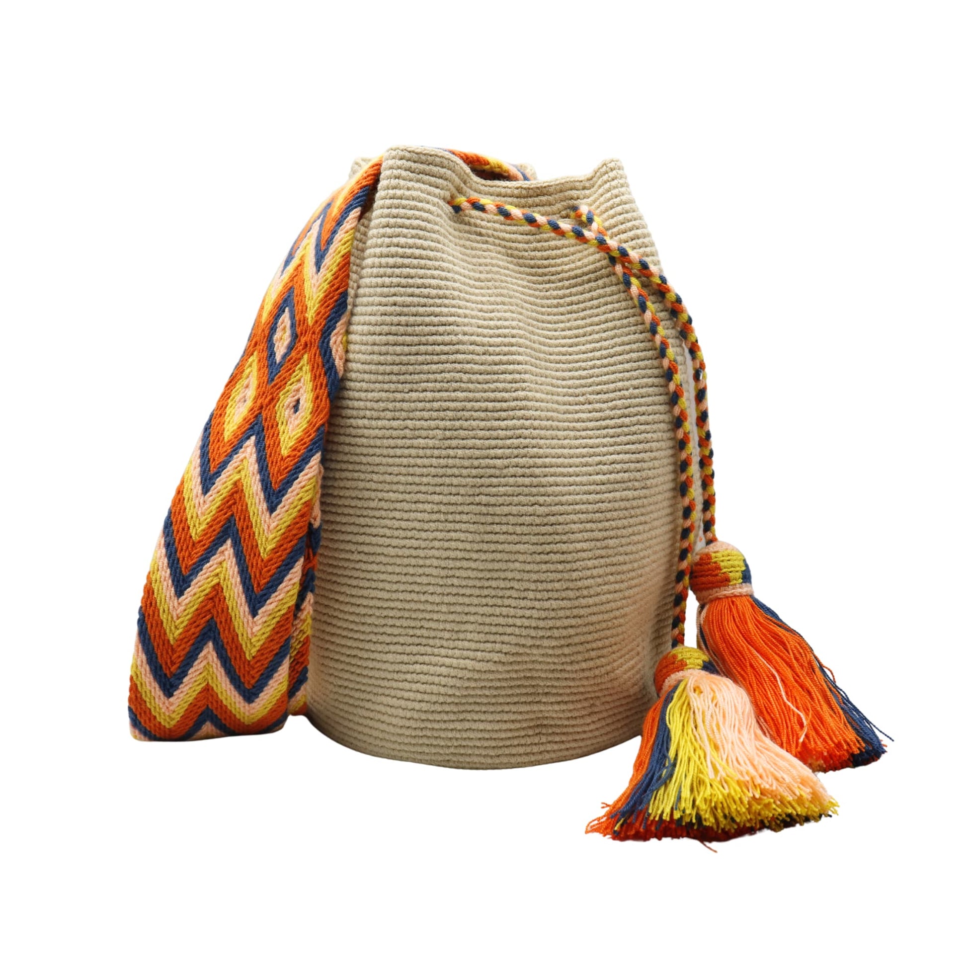 Beige handmade Wayuu bucket bag with a wide woven shoulder strap in orange, yellow, navy, and peach geometric chevron patterns. The bag features a braided drawstring closure with two large multicolored tassels and a soft, textured crochet body.